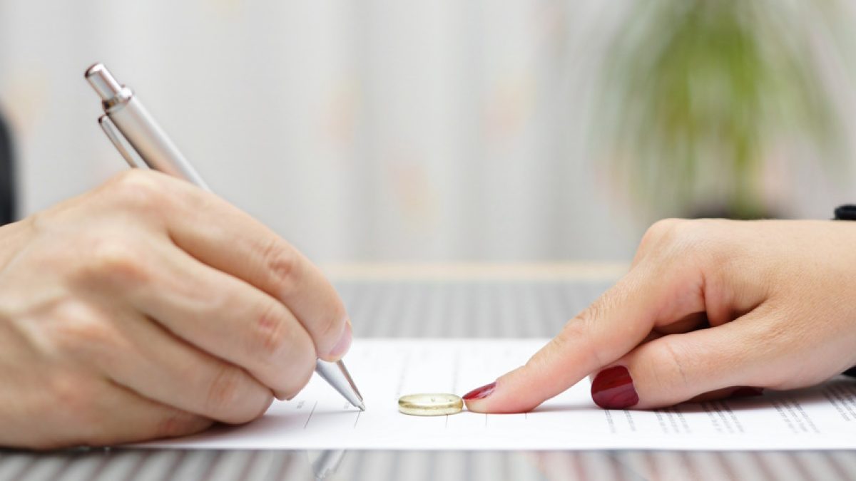 husband signing divorce agreement and woman push away weeding ring